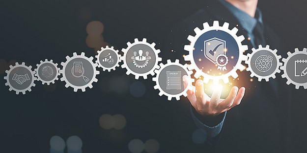 Mann im Hintergrund, der auf aneinandergereihte digitale Zahnräder zeigt