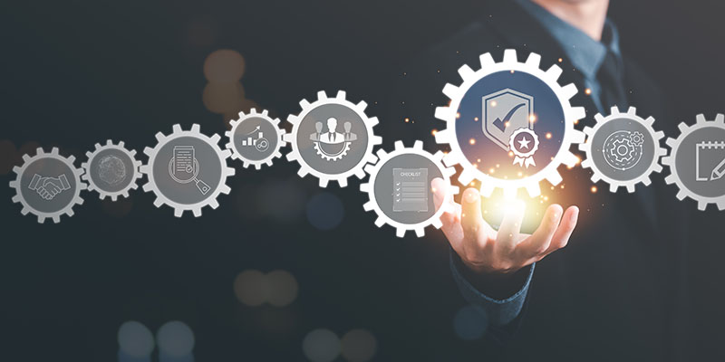 Mann im Hintergrund, der auf aneinandergereihte digitale Zahnräder zeigt