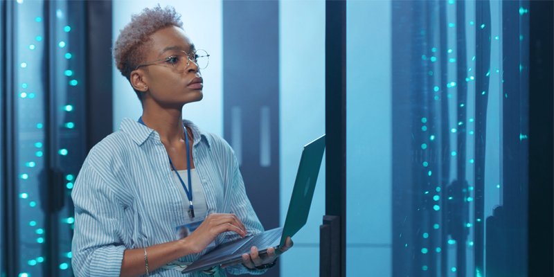 Frau mit Laptop in der Hand in einem Serverraum