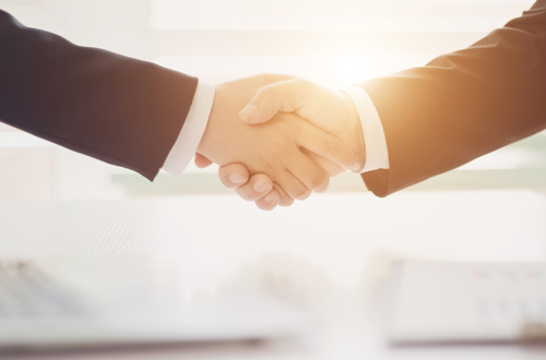 Sich schüttelnde Hände von zwei Anzugsträgern.